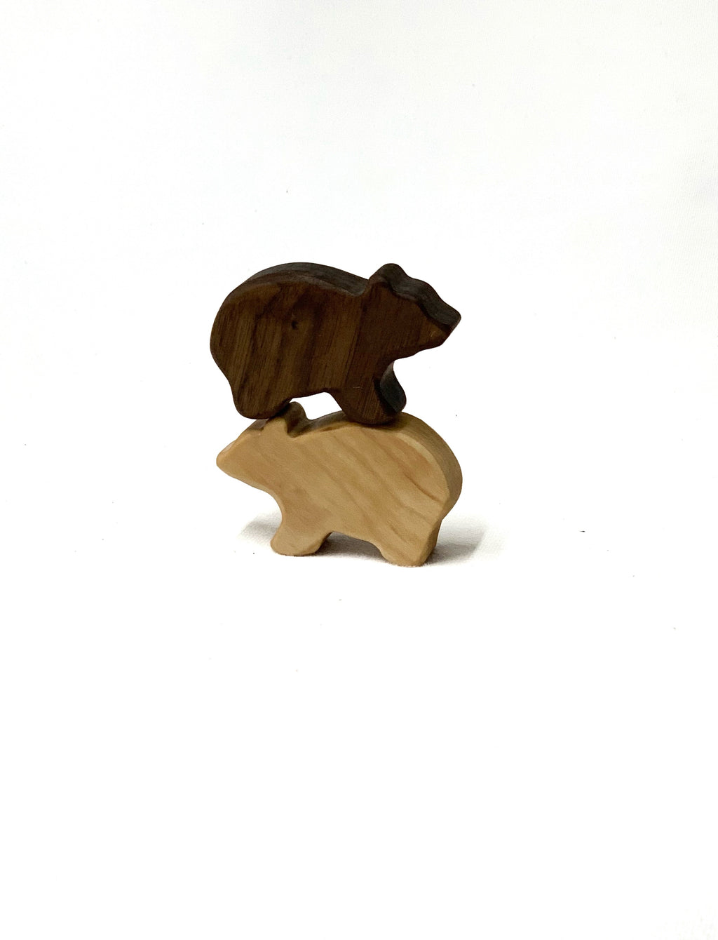 Two small handcrafted wooden bear figurines stacked on white background with natural wood grain visible