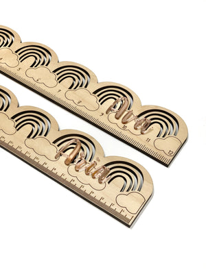 Natural wooden personalized rainbow ruler with engraved clouds and black curved stripes on light wood background