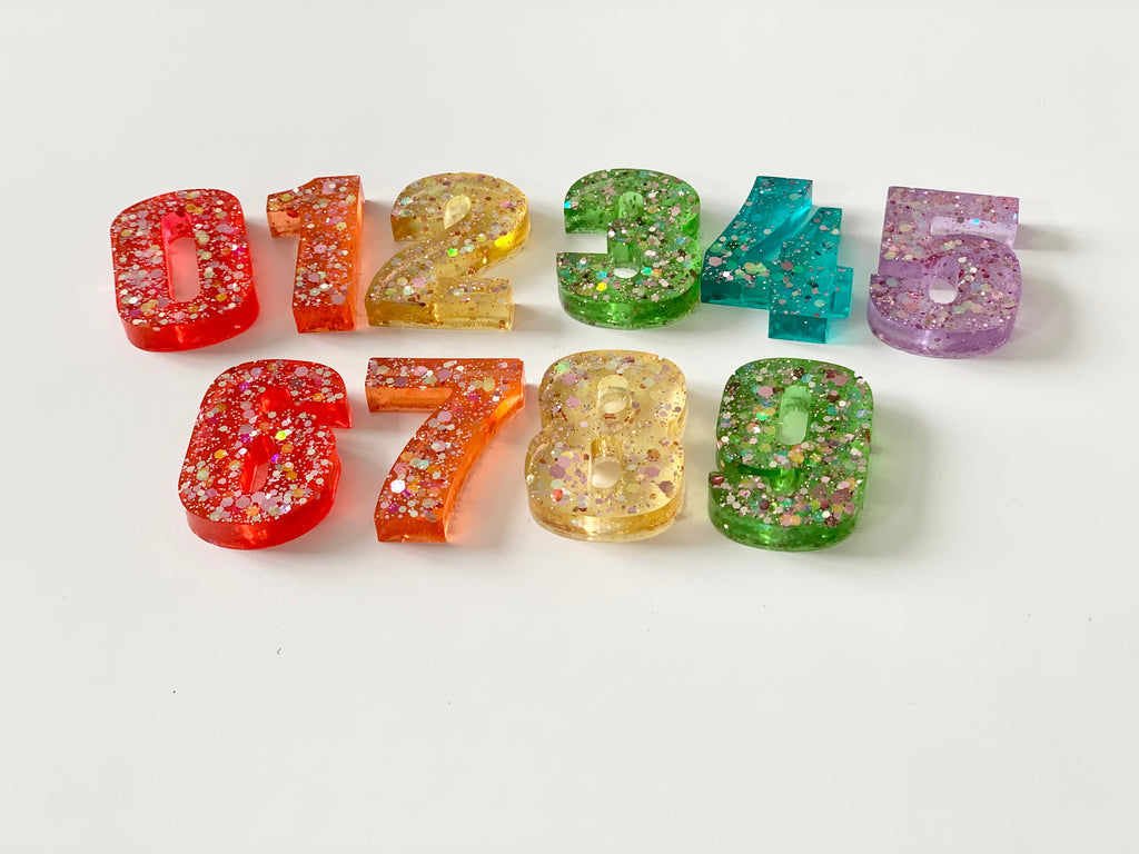 Rainbow glitter resin numbers set 0 to 9 with various bright colors on white background