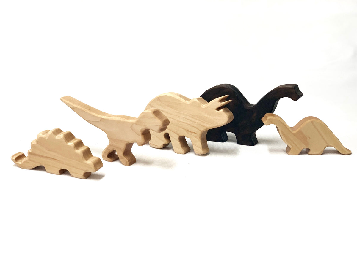 Set of natural and dark wooden dinosaur toy figurines including T Rex and other species on white background