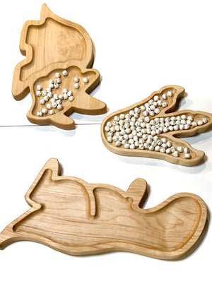 Natural wooden T-Rex sensory tray with compartments shaped like dinosaur body parts on white background