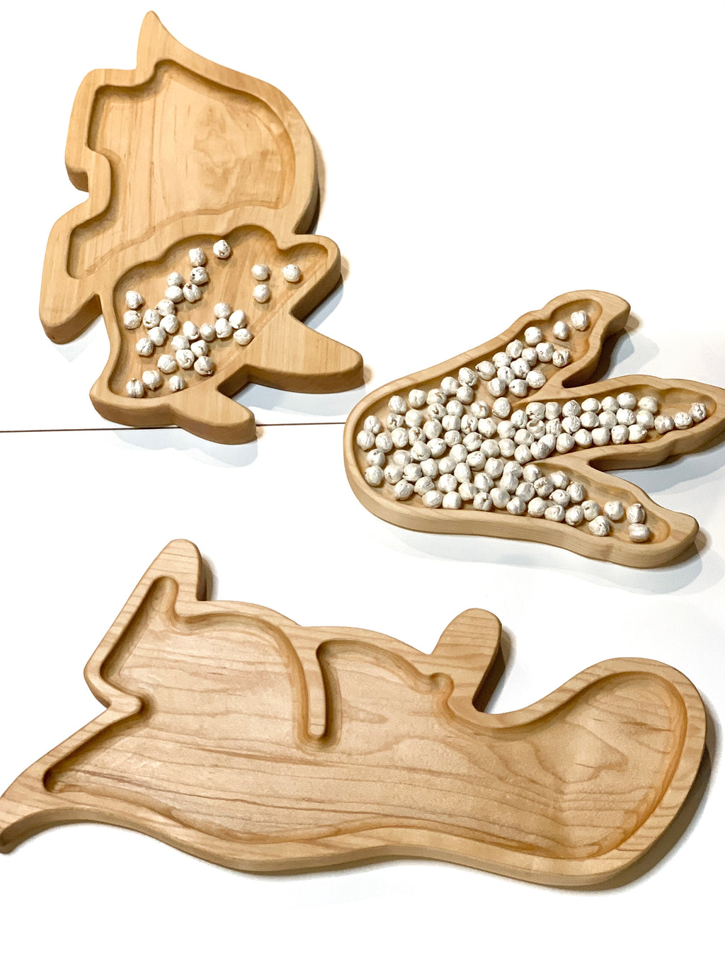 Natural wooden T-Rex sensory tray with compartments shaped like dinosaur body parts on white background