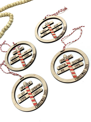 Round wooden North Pole family Christmas ornaments with red and white striped signposts and personalized names on white background