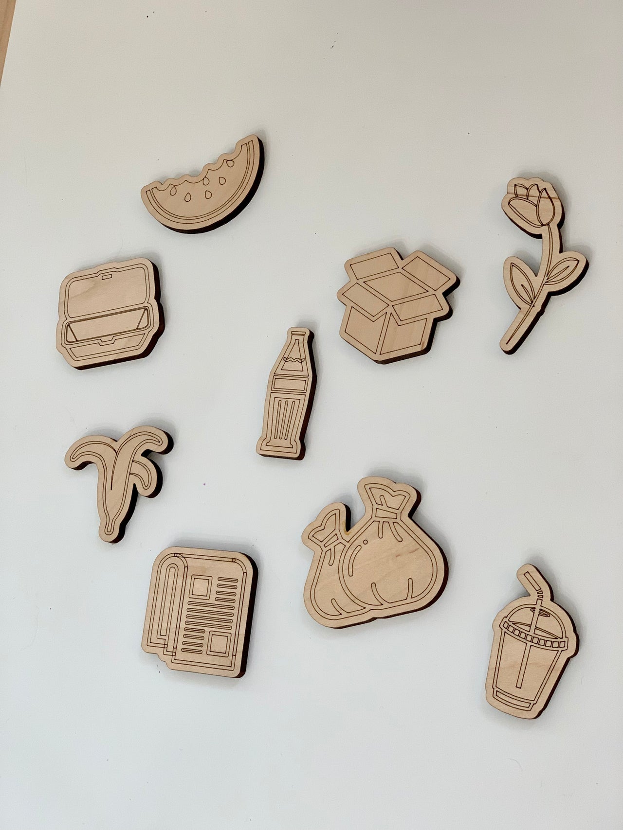 Set of nine wooden sorting pieces for garbage, recycling, and compost with various food and waste shapes on white background