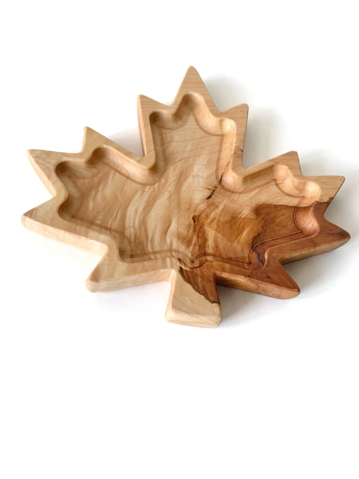Hand-carved maple leaf-shaped wooden plate with natural wood grain and smooth finish on white background